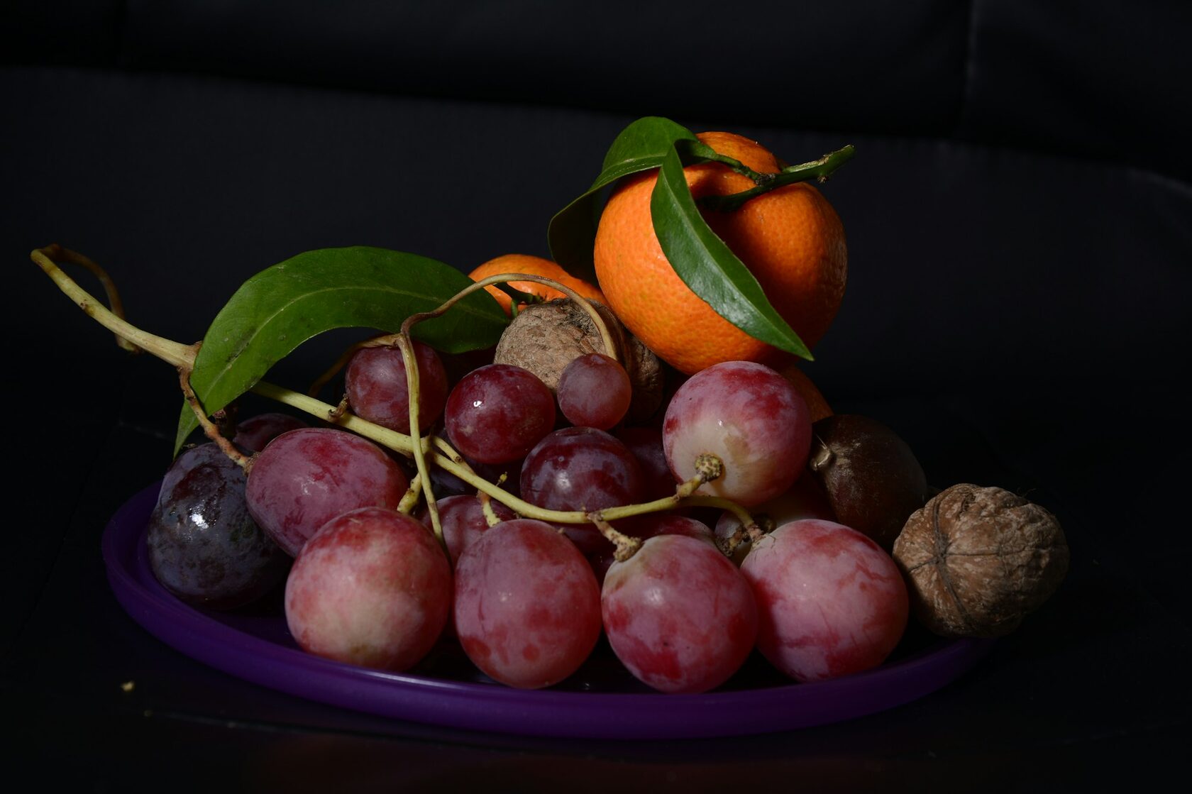 A vibrant platter of premium Mexican tropical fruits including mango, pineapple, papaya, watermelon and strawberries on a purple background.