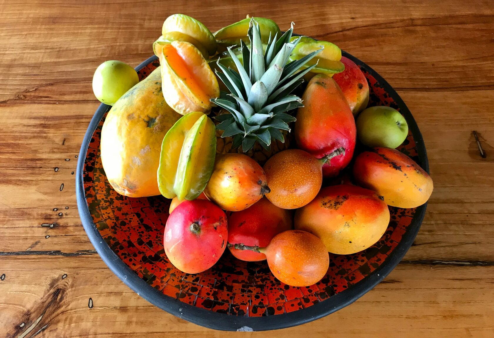 A wooden crate filled with fresh Mexican tropical fruit: mango, papaya, pineapple and oranges.